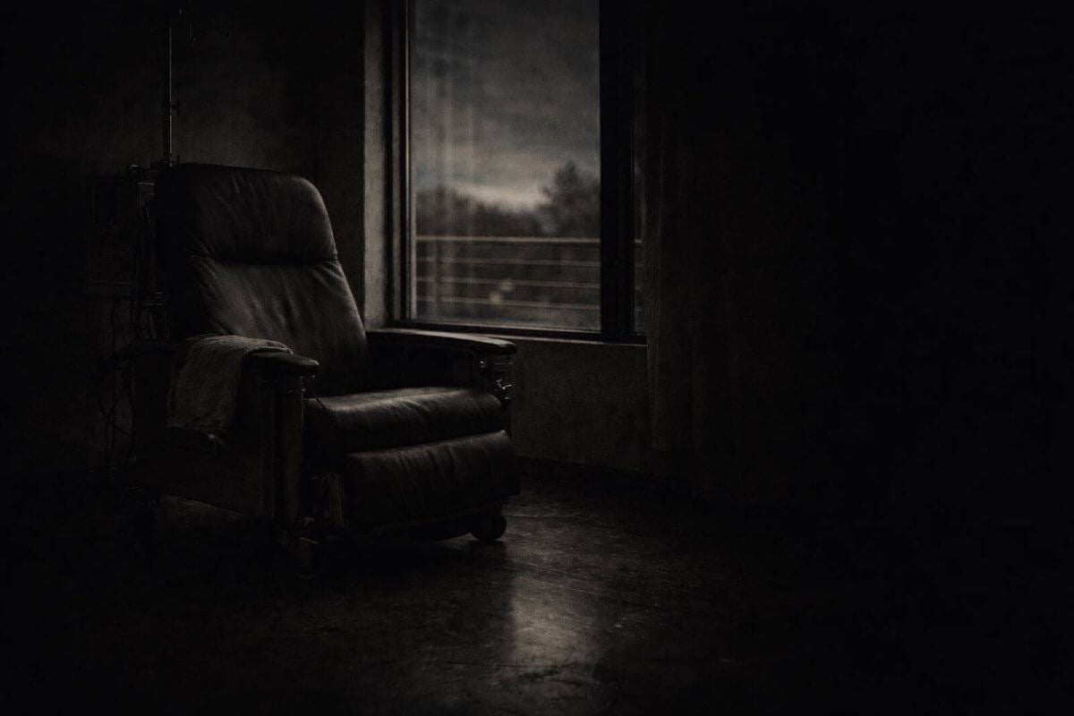 Dark room with a single chair by a window, representing isolation, survival, and the moment nobody came so you carried it anyway